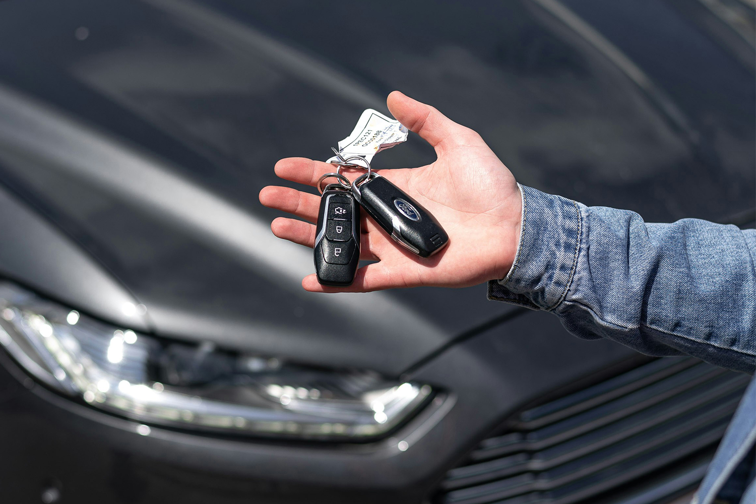 A man holding keys to a new car made by Ford with the vehicle in the background