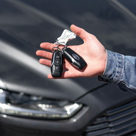 A man holding keys to a new car made by Ford with the vehicle in the background