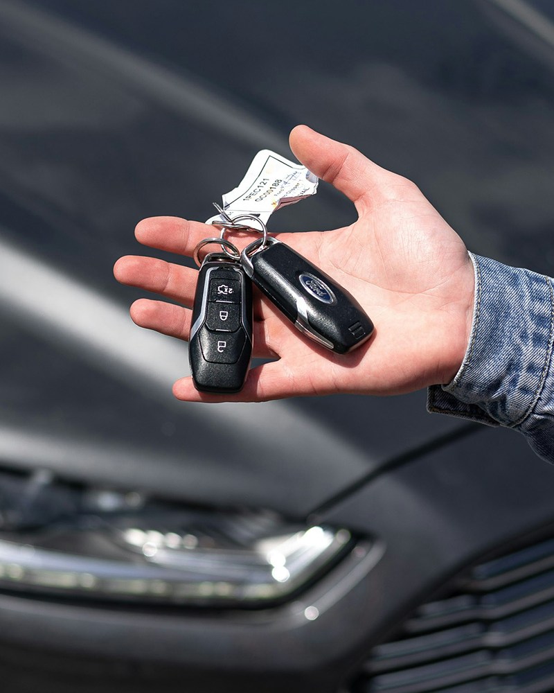 A man holding keys to a new car made by Ford with the vehicle in the background