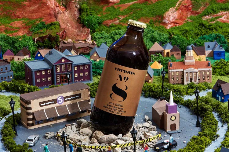 Curious Elixirs No. 8 bottle on top of a model fo a town