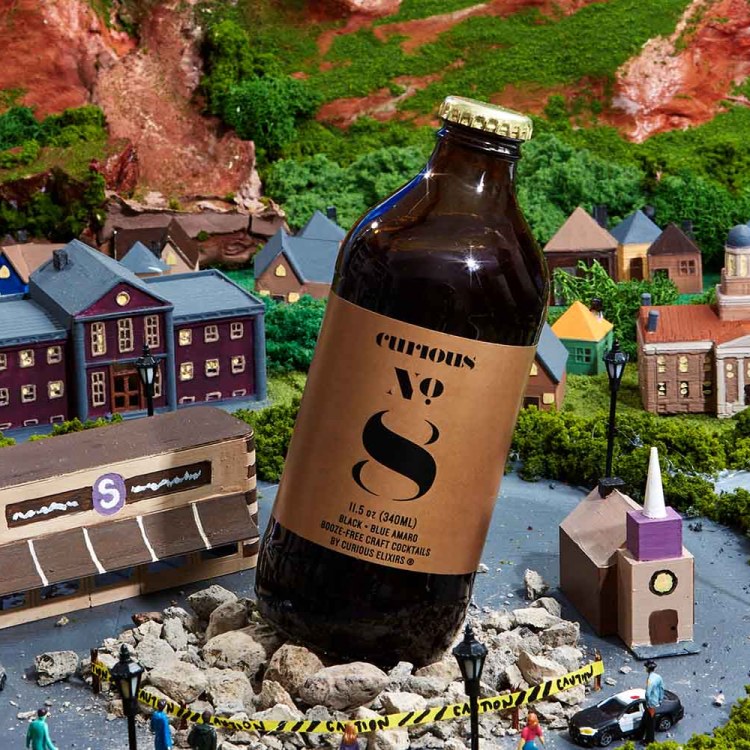 Curious Elixirs No. 8 bottle on top of a model fo a town
