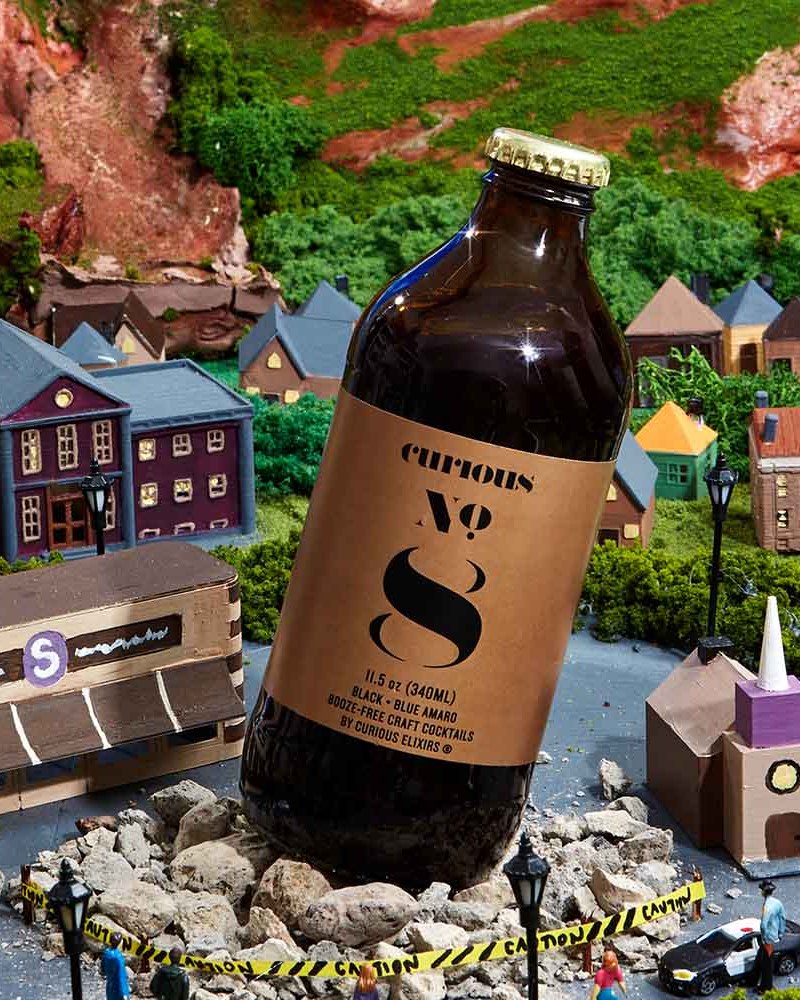 Curious Elixirs No. 8 bottle on top of a model fo a town