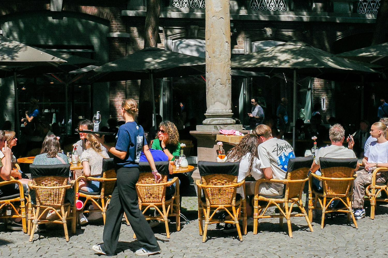 A waitress serving early dinner at an outdoor restaurant.