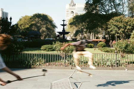 A pair of skaters doing tricks in a park.