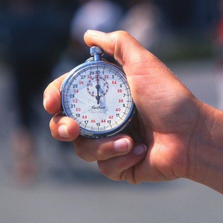 A close-up of a man holding a vintage racing stopwatch.