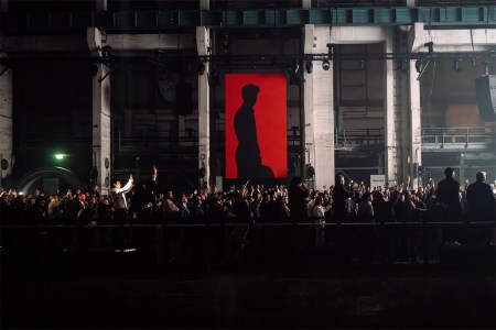 A red banner with F1 driver Gabriel Bortoleto shown in silhouette, at the Audi Revolut F1 Team launch event in Berlin