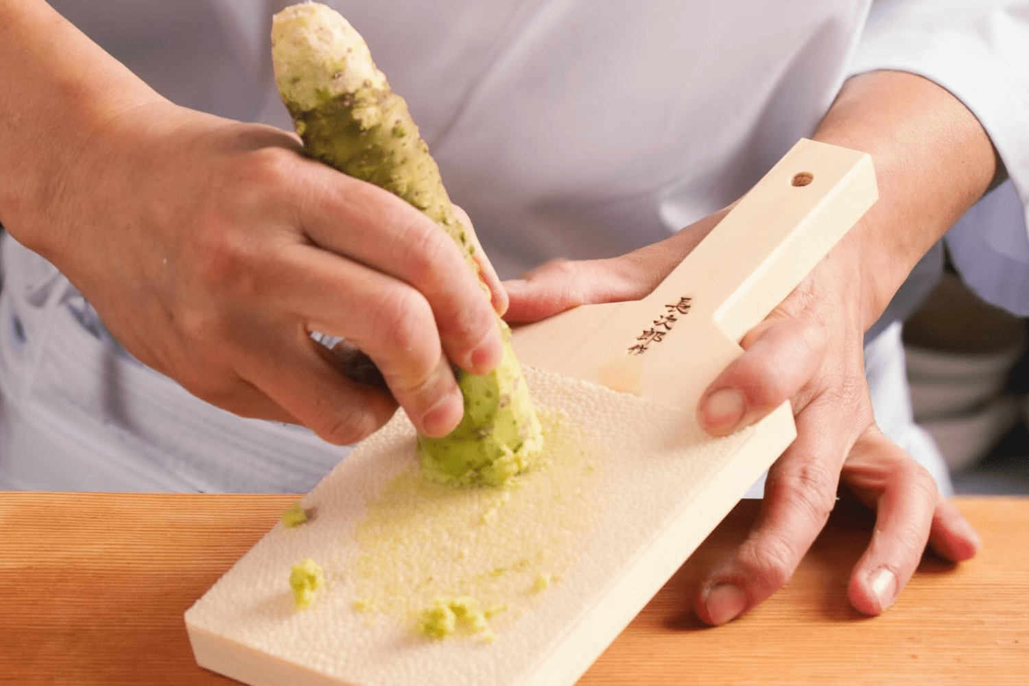 chef grating wasabi on a board