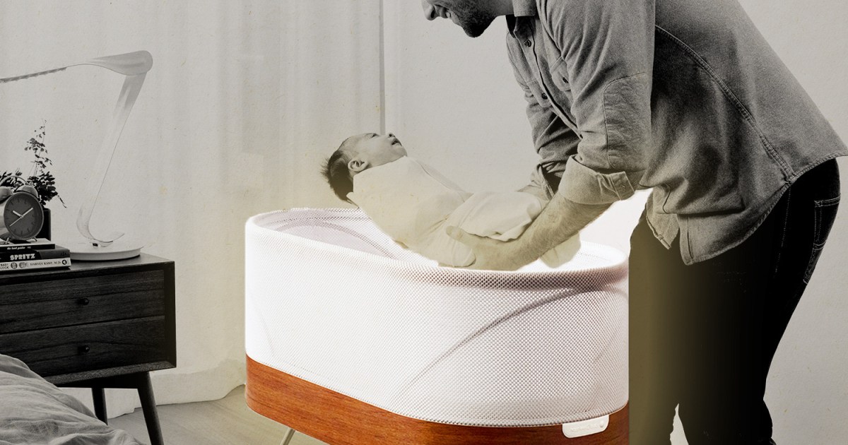 A dad picking up his infant out of the Snoo, a smart sleeper bassinet from Dr. Harvey Karp's company Happiest Baby. Here's our full review of the Snoo.