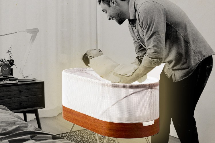 A dad picking up his infant out of the Snoo, a smart sleeper bassinet from Dr. Harvey Karp's company Happiest Baby. Here's our full review of the Snoo.