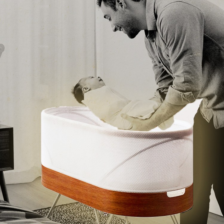 A dad picking up his infant out of the Snoo, a smart sleeper bassinet from Dr. Harvey Karp's company Happiest Baby. Here's our full review of the Snoo.