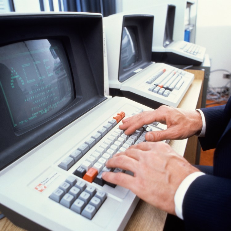 A man typing on an old keyboard.