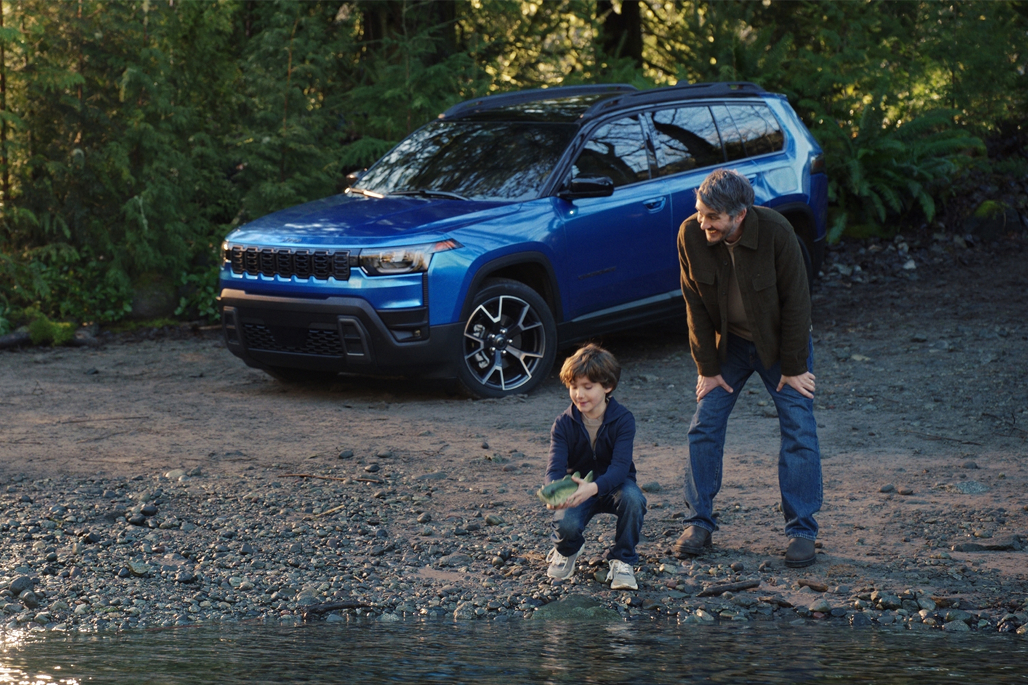 A still image from Jeep's Super Bowl ad from 2026, "Billy Goes to the River," which shows a boy setting a Big Mouth Billy Bass free alongside his dad and a 2026 Jeep Cherokee hybrid