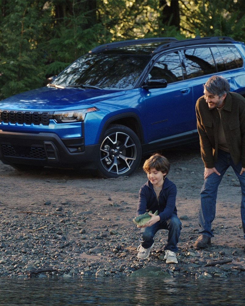 A still image from Jeep's Super Bowl ad from 2026, "Billy Goes to the River," which shows a boy setting a Big Mouth Billy Bass free alongside his dad and a 2026 Jeep Cherokee hybrid