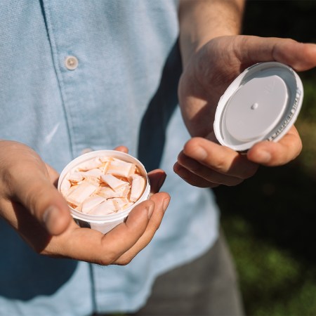 A man opening a container of nicotine pouches, or snus. The stimulant is gaining ground among wellness influencers.