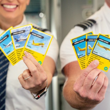 Two Spirit Airlines pilots holding up new trading cards featuring their various Airbus airplanes
