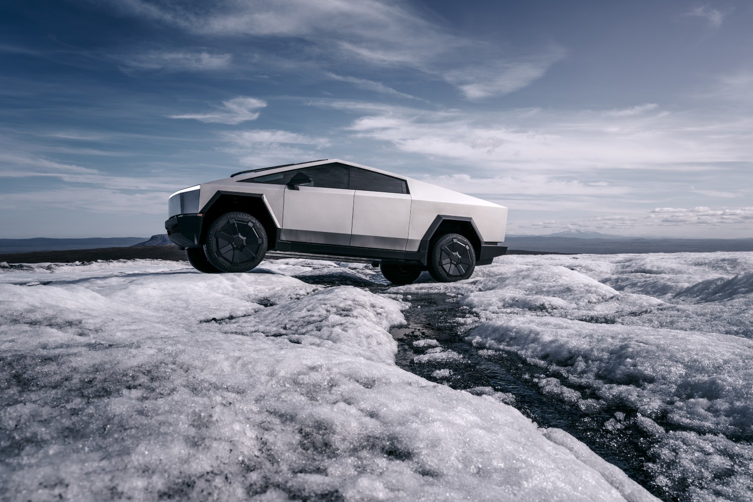 The electric Tesla Cybertruck driving across a frozen landscape
