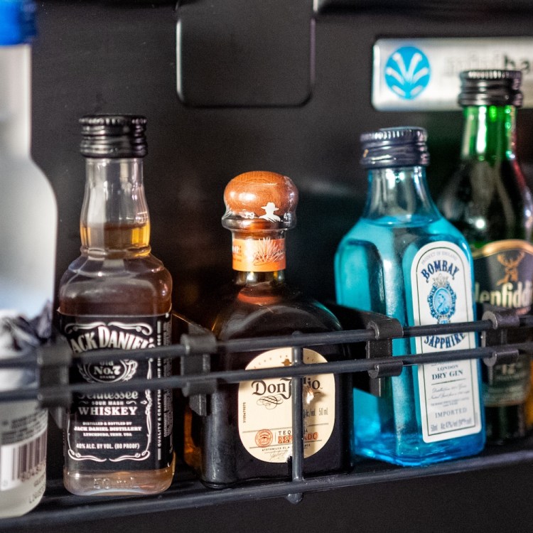 Various drinks are visible inside a hotel minibar refrigerator