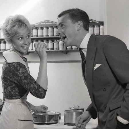 In the kitchen 1950s. A young couple in their kitchen. She is making him taste the food and puts a spoon in his mouth. Sweden 1959 Kristoffersson ref CG35 (Photo by Sjöberg Bildbyrå/ullstein bild via Getty Images)