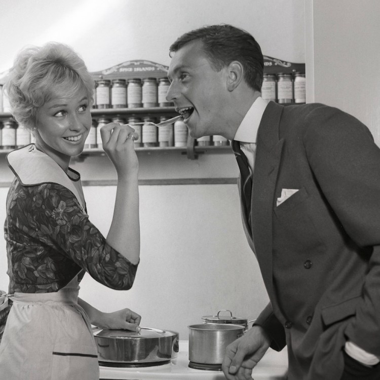 In the kitchen 1950s. A young couple in their kitchen. She is making him taste the food and puts a spoon in his mouth. Sweden 1959 Kristoffersson ref CG35 (Photo by Sjöberg Bildbyrå/ullstein bild via Getty Images)