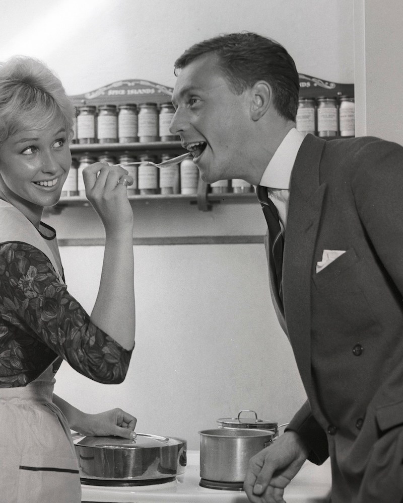 In the kitchen 1950s. A young couple in their kitchen. She is making him taste the food and puts a spoon in his mouth. Sweden 1959 Kristoffersson ref CG35 (Photo by Sjöberg Bildbyrå/ullstein bild via Getty Images)