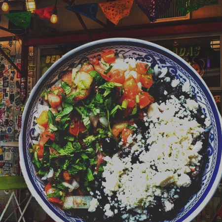a bowl of rice and beans with cheese and pico de gallo overlaid on a photo of SoHo restaurant La Esquina
