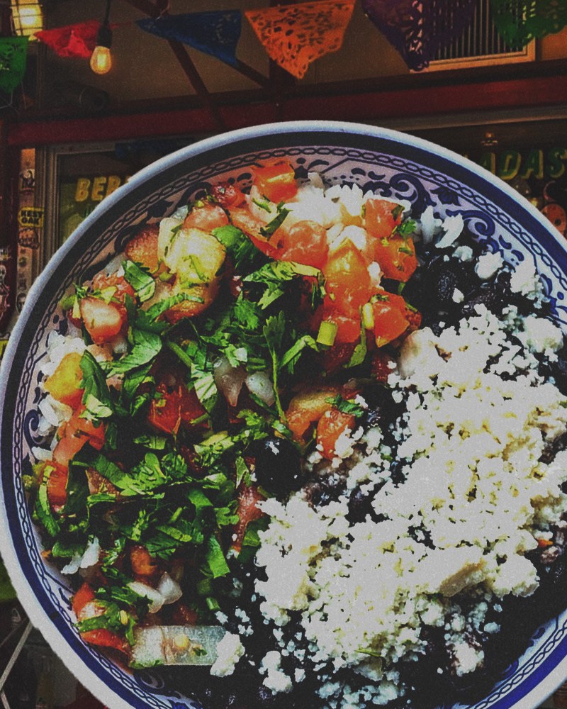 a bowl of rice and beans with cheese and pico de gallo overlaid on a photo of SoHo restaurant La Esquina