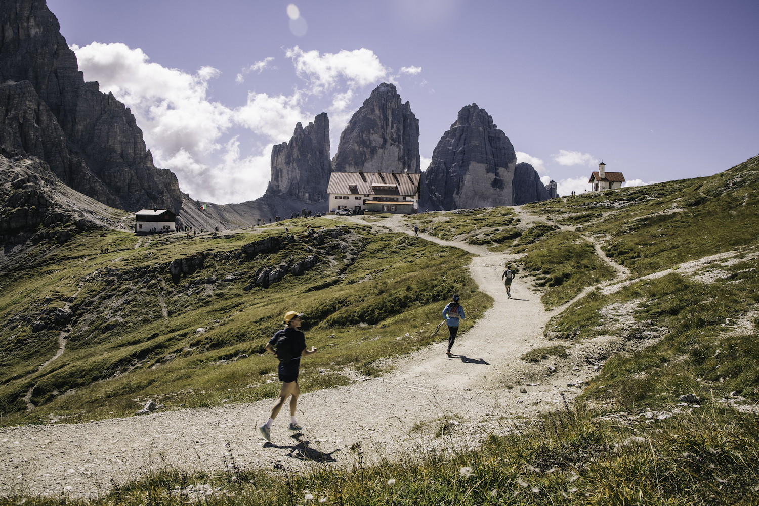 Three runners ascend a trail in the mountains on a hut-to-hut running and hiking route