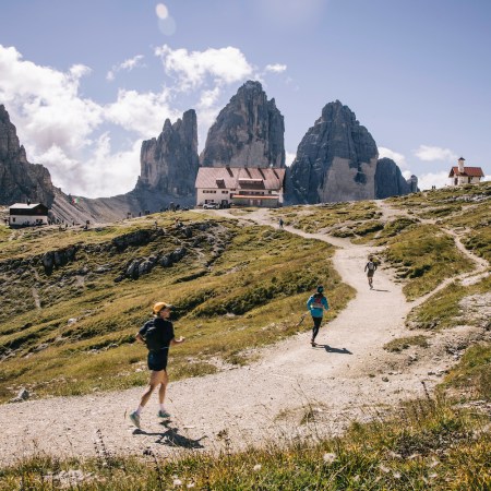 Three runners ascend a trail in the mountains on a hut-to-hut running and hiking route
