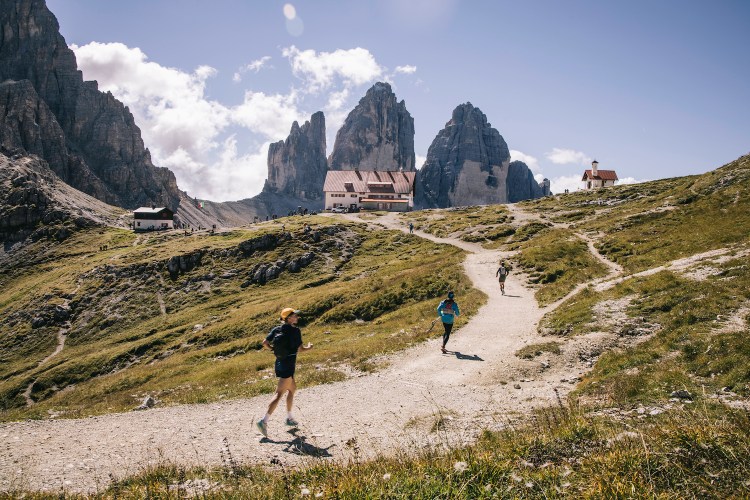 Three runners ascend a trail in the mountains on a hut-to-hut running and hiking route