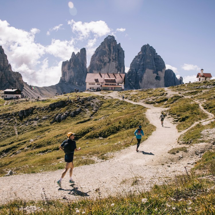 Three runners ascend a trail in the mountains on a hut-to-hut running and hiking route