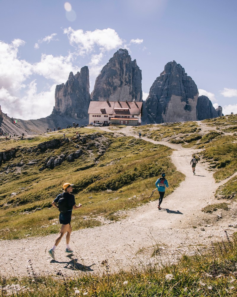 Three runners ascend a trail in the mountains on a hut-to-hut running and hiking route