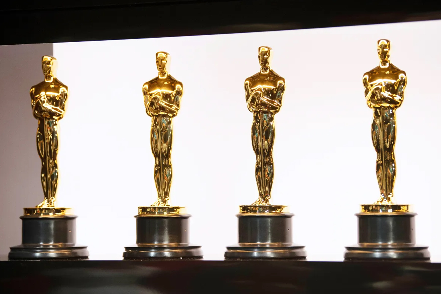 Four Oscar statuettes lined up in a row