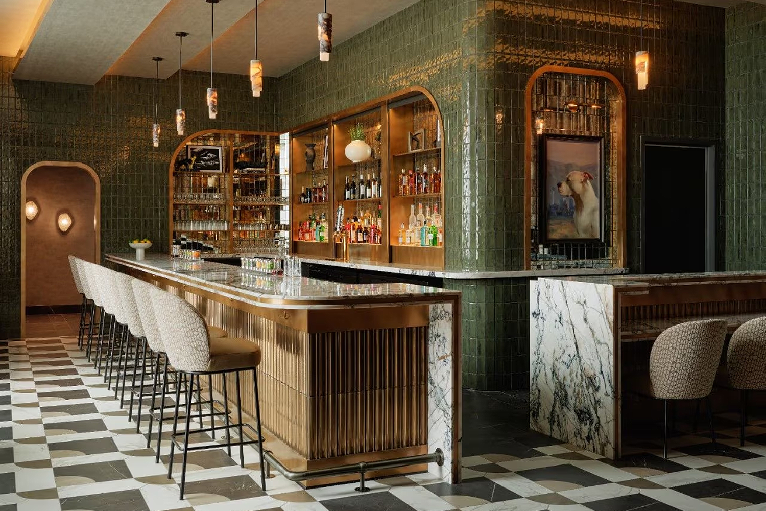 Speakeasy-style bar inside the American Express Centurion Lounge Sidecar in Las Vegas, with green tiled walls, a marble bar, pendant lighting, upholstered stools and shelves of spirits creating an intimate, hidden-lounge atmosphere.