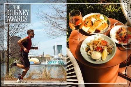 A man running next to a body of water next to a table with three plates of food and a wine glass