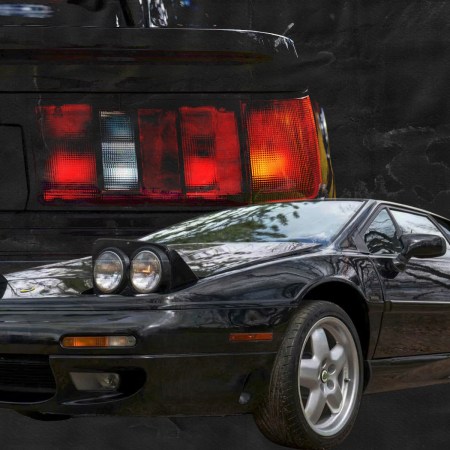 A black car in the foreground with a red, white and orange taillight behind it