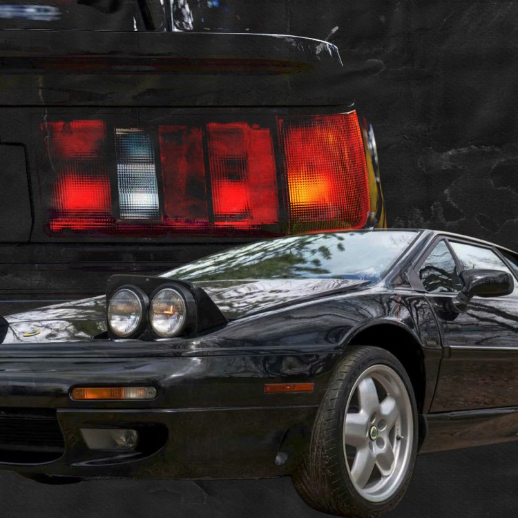 A black car in the foreground with a red, white and orange taillight behind it