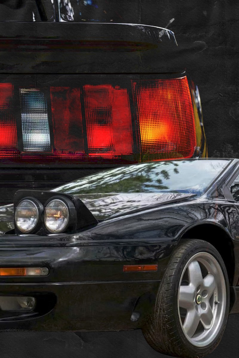 A black car in the foreground with a red, white and orange taillight behind it