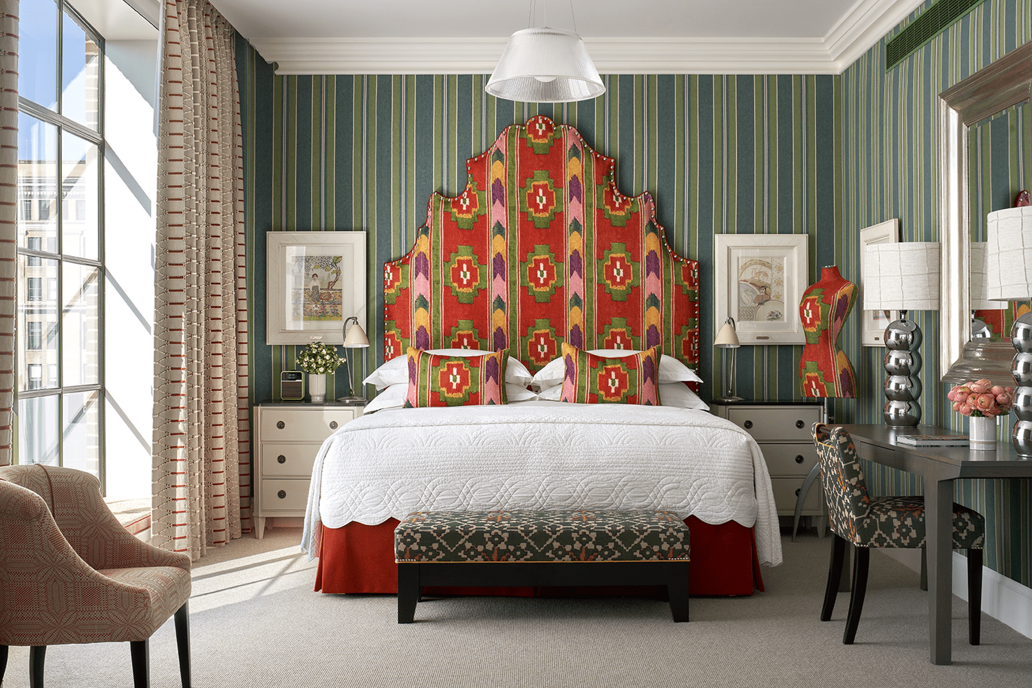 Guestroom at Crosby Street Hotel in New York featuring vibrant contemporary design with patterned textiles, curated artwork, modern furnishings and large windows bringing in natural light.