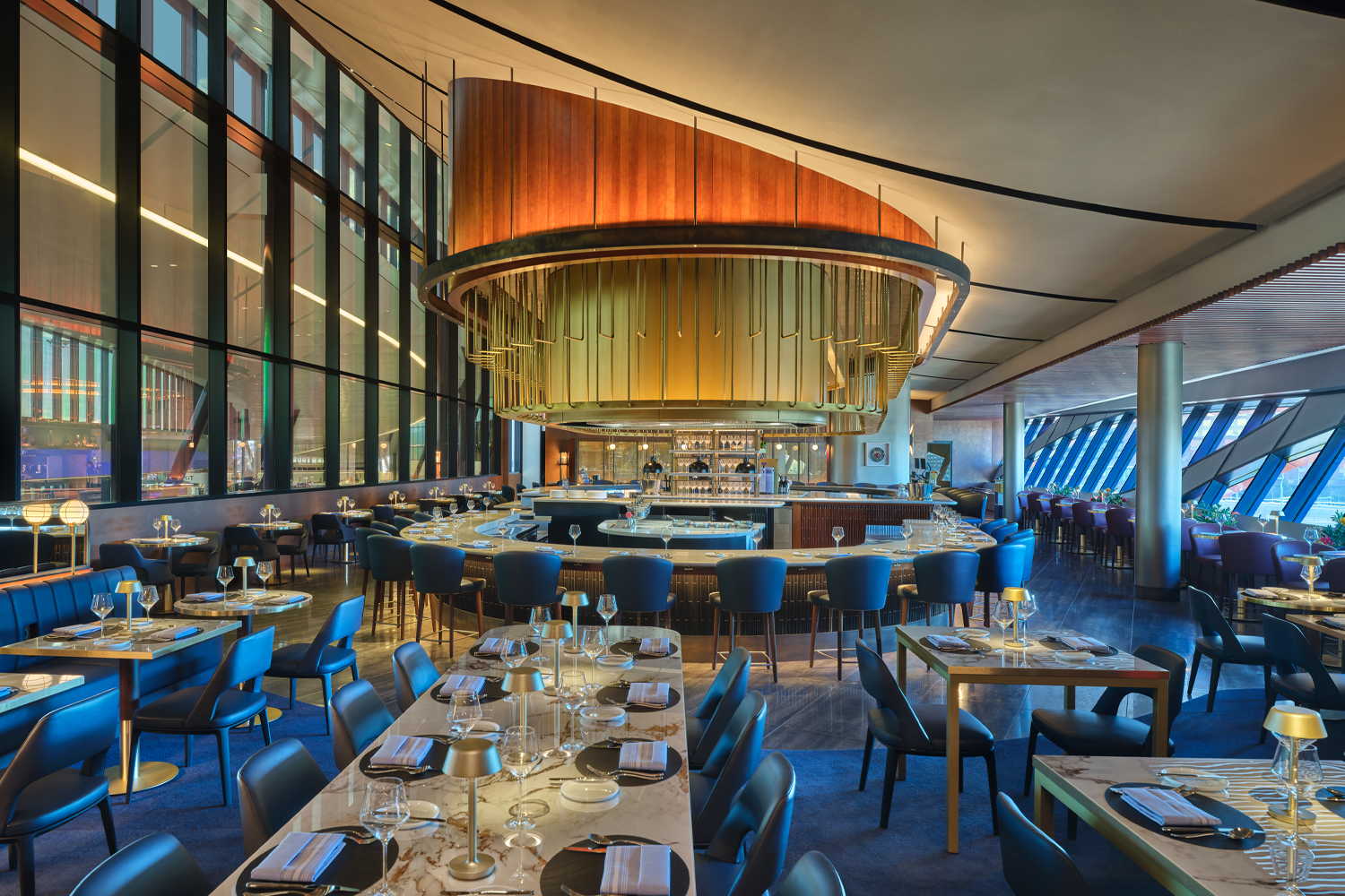 Boston’s Delta One Lounge interior, featuring a sleek, modern design with warm lighting, plush seating areas and a refined dining space reserved for premium Delta passengers.