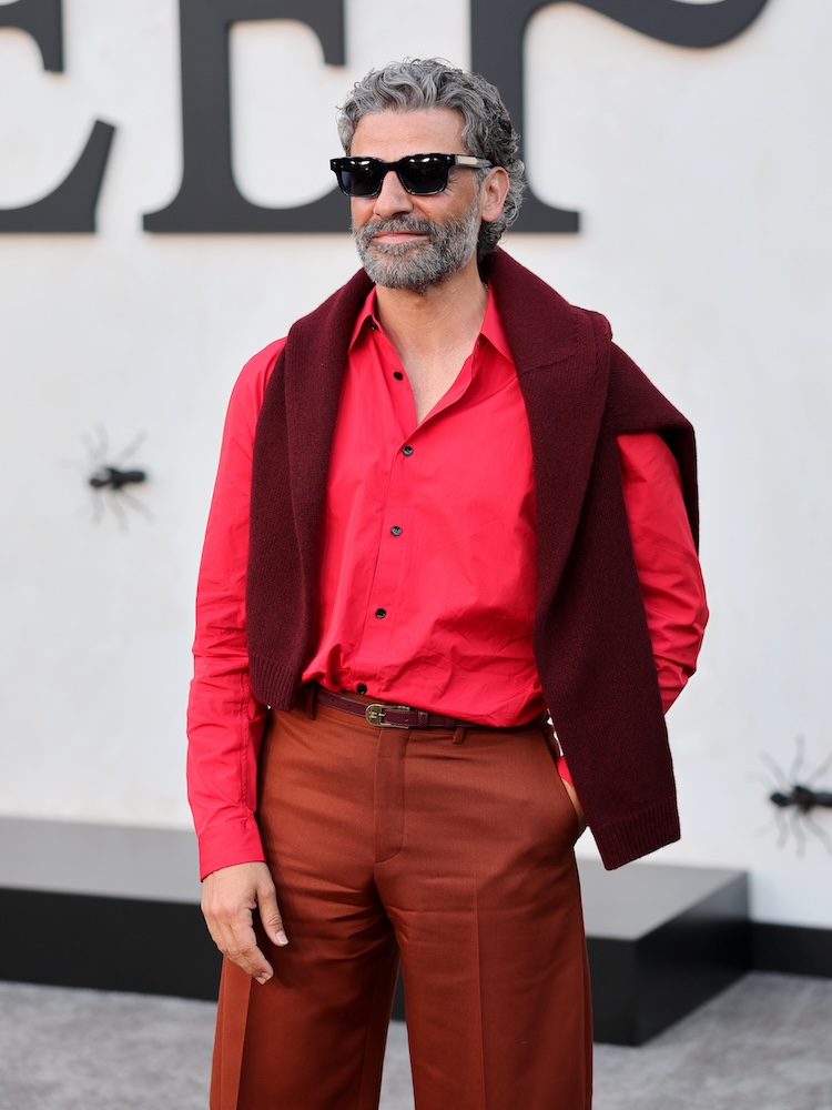A man in a red shirt with burgundy pants, a maroon sweater around his shoulders and sunglasses