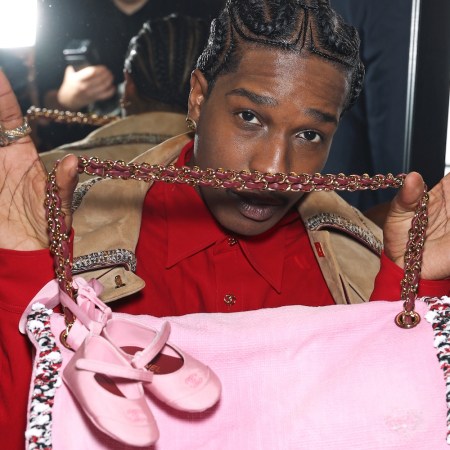 A man holding up a pink bag with baby ballet flats attached to the handle