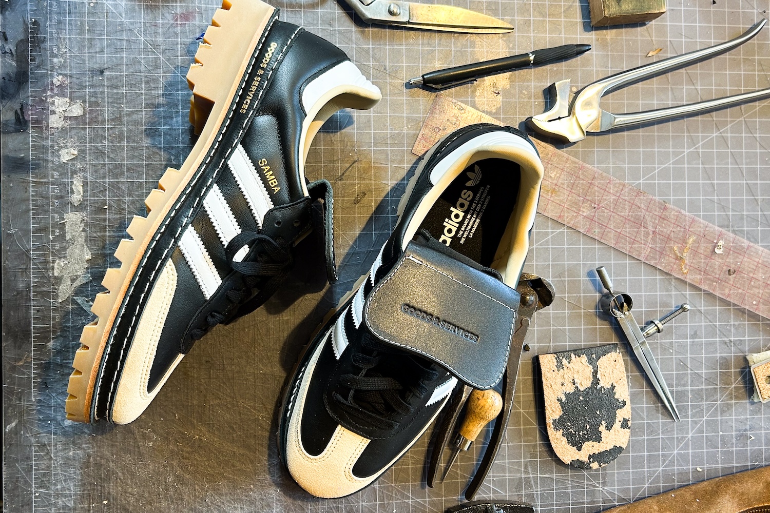 A pair of shoes sitting on a work table with tools scattered around them