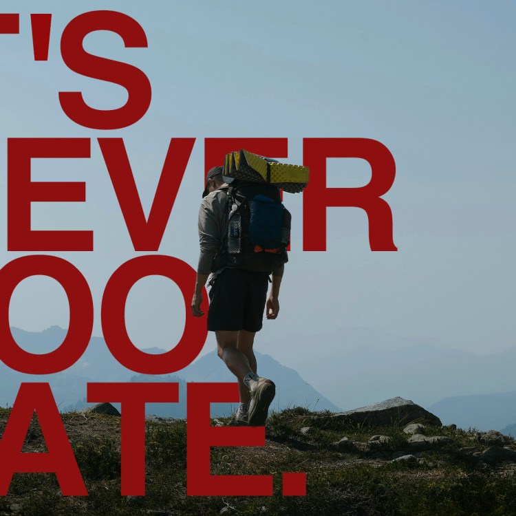 A man rucking on a trail with a backpack filled with weights. Over top, there is text that reads: It's Never Too Late.