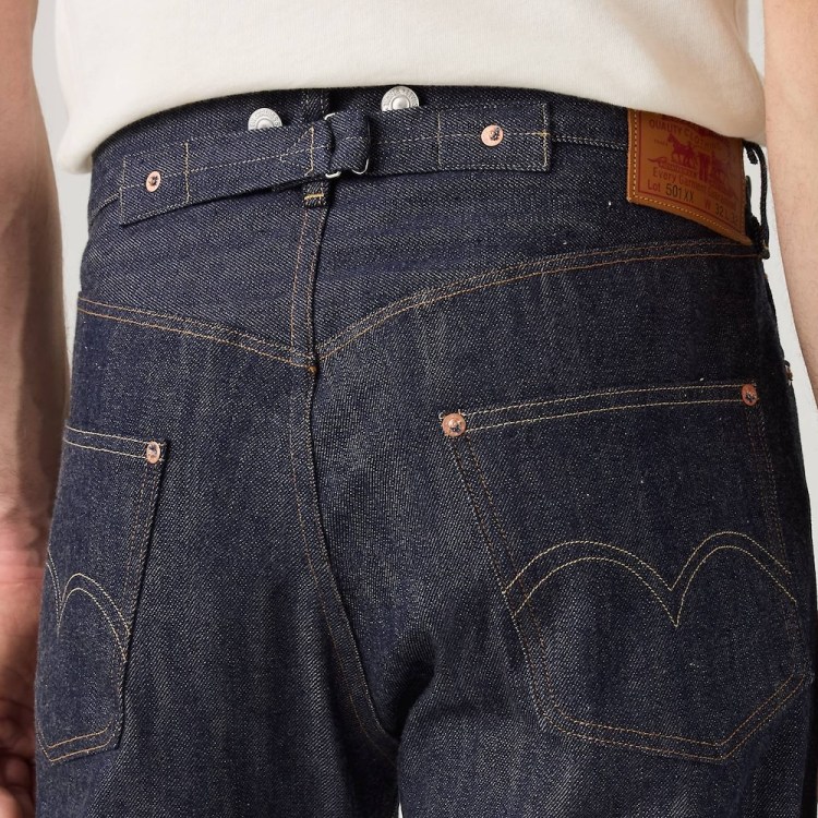 Close-up of the back of a person wearing dark wash denim jeans with a cinch-back, suspender buttons, and a Levi's patch.