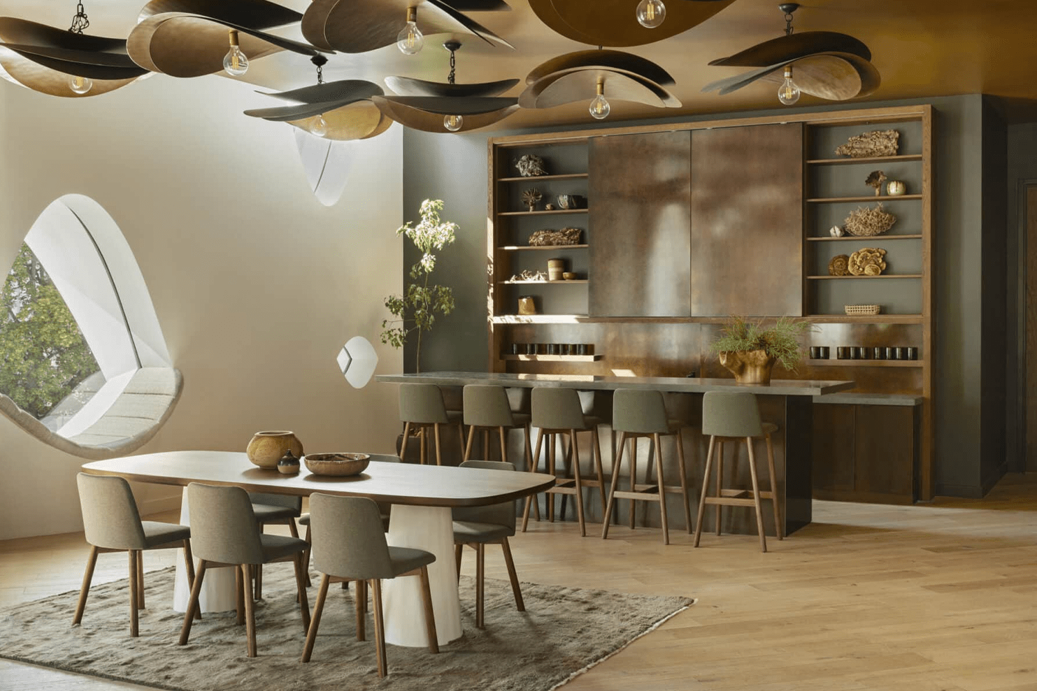 Communal lounge area at 1 Hotel Central Park featuring a long wooden dining table, small bar, soft lighting, natural materials and greenery, creating a cozy shared space for dining and socializing.