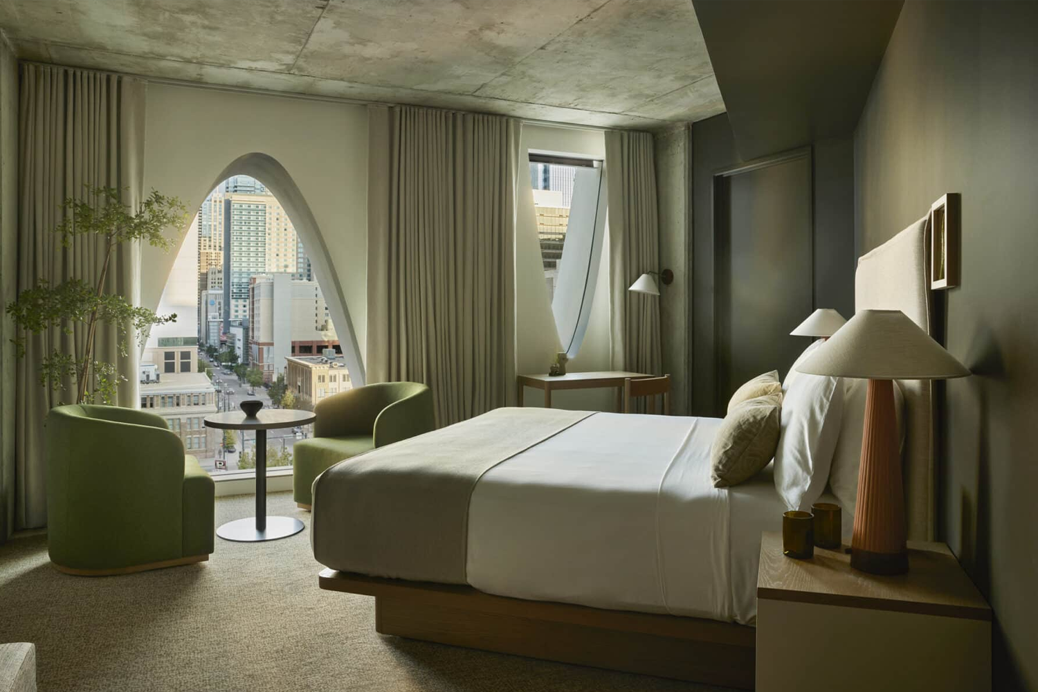 Guestroom suite at Populus Denver featuring contemporary, nature-inspired design with large windows bringing in natural light, a neutral color palette, streamlined furnishings and soft textural accents that create a serene, modern hotel interior.