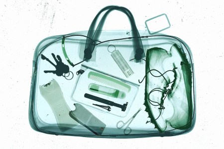 X-ray image of a duffel bag showing multiple prohibited items inside, including liquids and other flagged objects, highlighted during airport security screening.