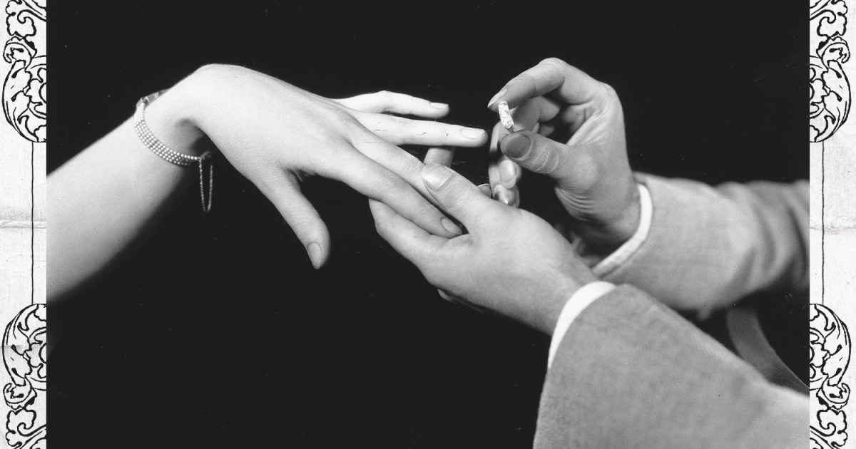 A man placing a diamond engagement ring on the hand of a woman