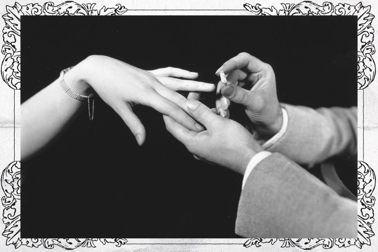 A man placing a diamond engagement ring on the hand of a woman