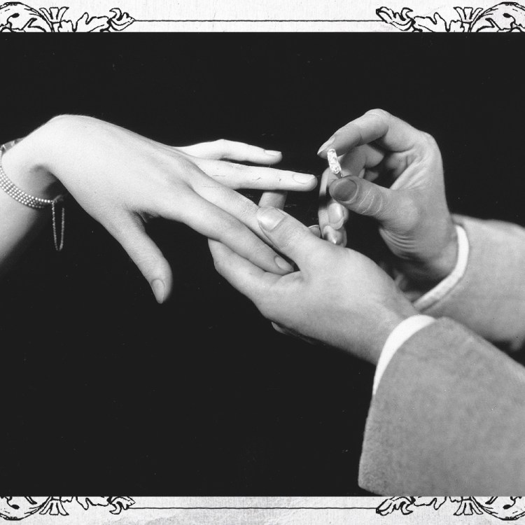 A man placing a diamond engagement ring on the hand of a woman